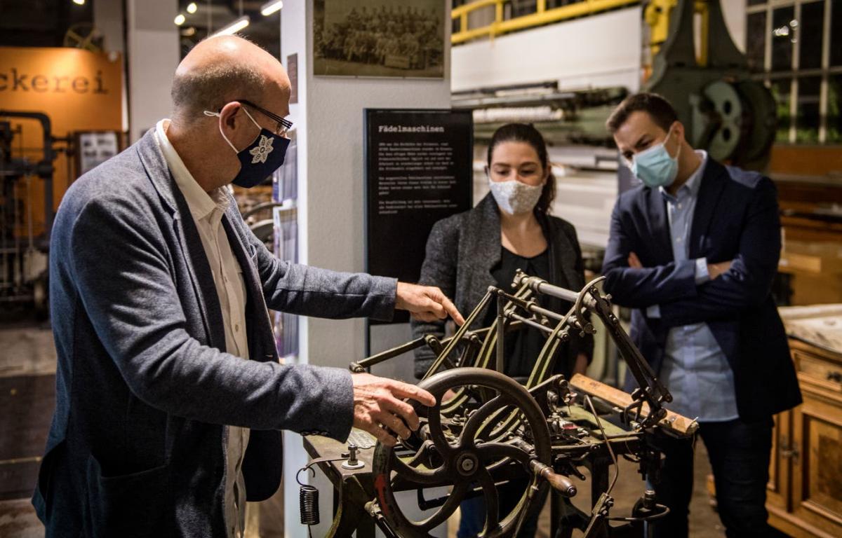 Silvio Delgrosse erklärt bei der Ausstellungseröffnung Besuchern die Funktionsweise einer Fädelmaschine.